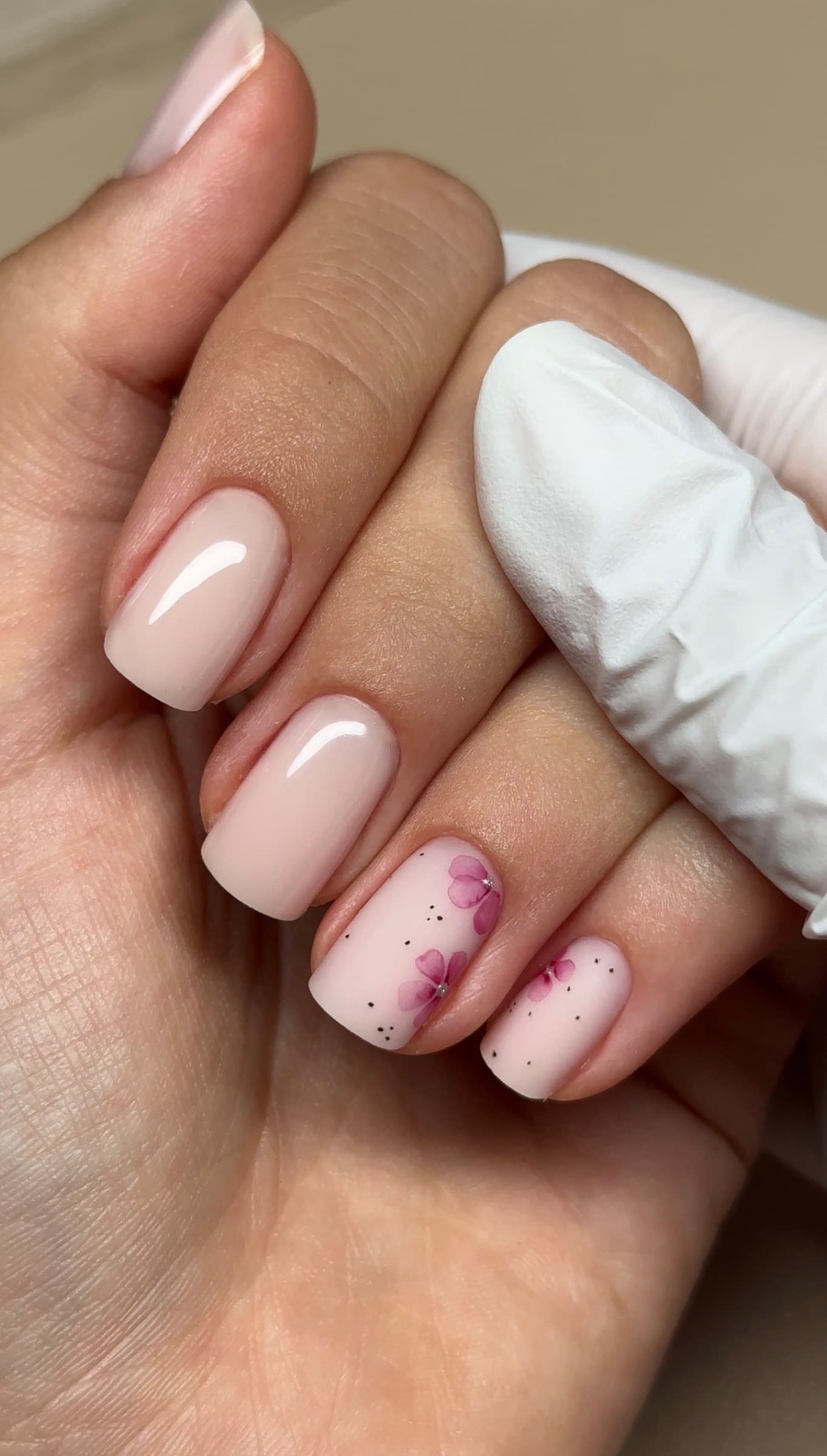 Glossy nude square manicure with a hand-painted pink floral accent nail