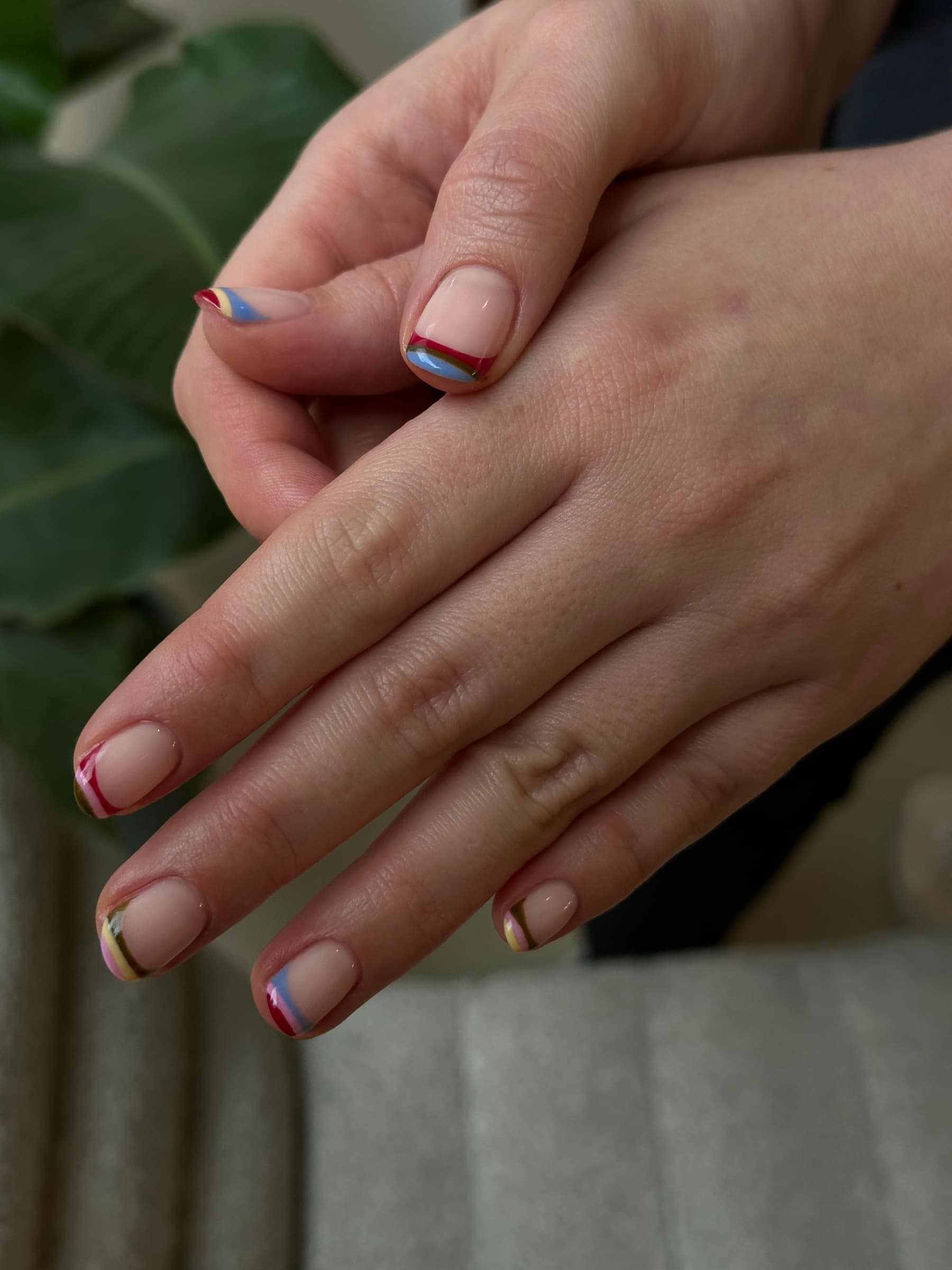Short square nails with a thin multicolor line French tip in red, blue, olive, and yellow