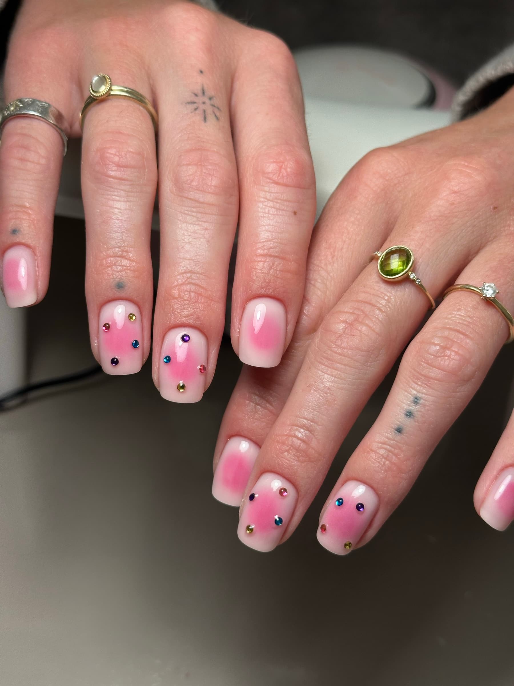 Nude gel nails with a soft pink bloom effect and scattered rhinestones