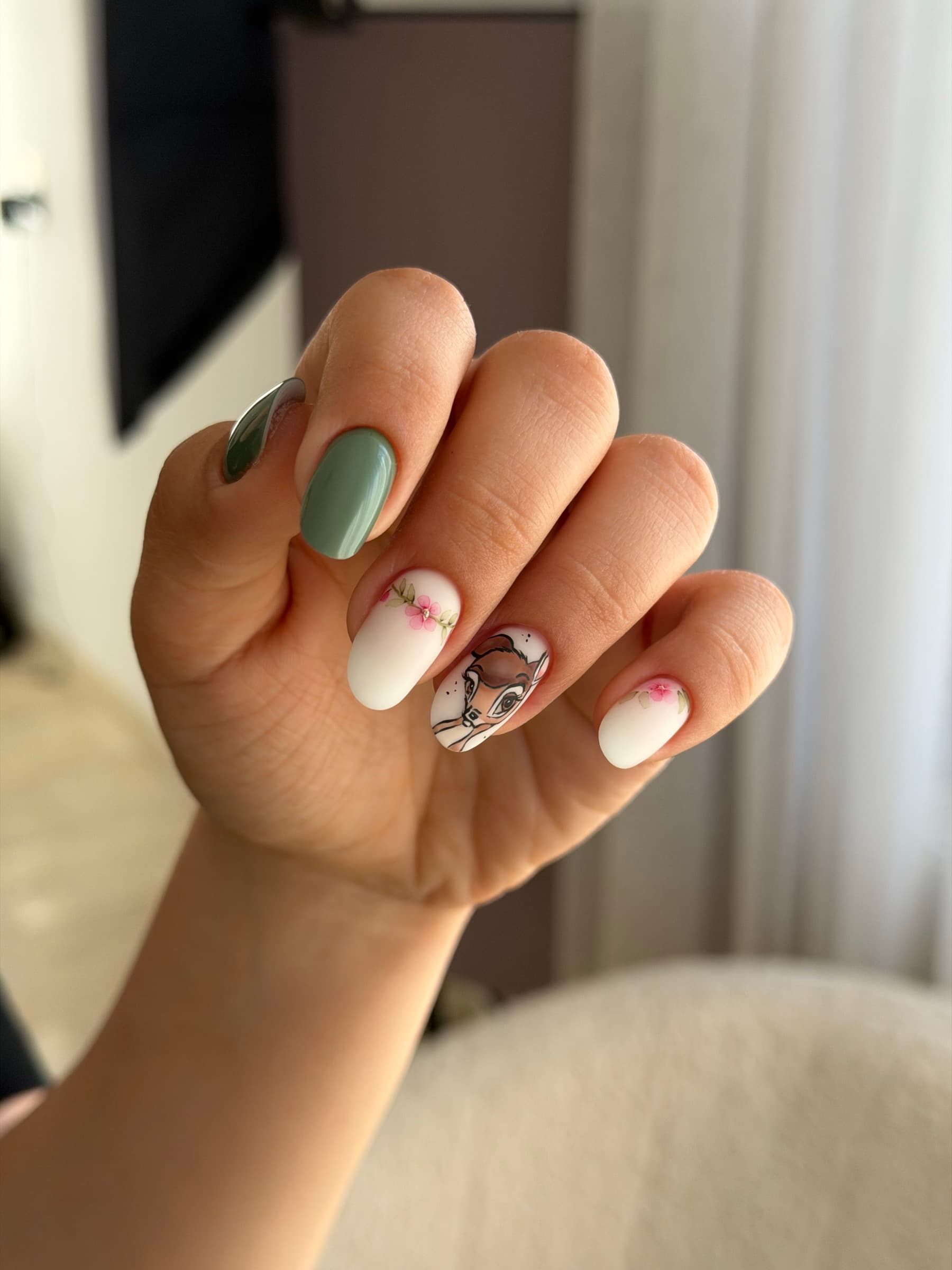 White nails with hand-painted florals and a hand-painted deer accent nail, paired with a glossy sage green nail